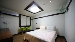 A bedroom with a bed, a desk, a chair, a ceiling fan, and a skylight. - Castle Motel Iksan (Iksan)