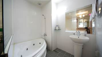 A modern bathroom with a freestanding bathtub, a pedestal sink, and a mirror above the sink.