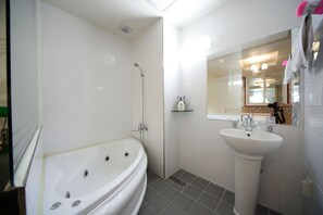 A modern bathroom with a freestanding bathtub, a pedestal sink, and a mirror above the sink.