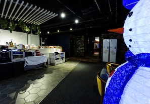 Interior de restaurante con mostrador, baldosas hexagonales en el suelo, plantas colgantes y una decoración de muñeco de nieve.