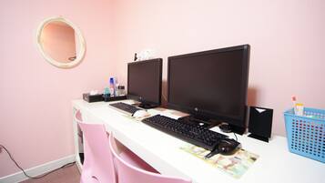 Una habitación con un escritorio blanco, dos monitores, un teclado, un ratón, un espejo y una silla rosa.