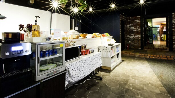 Una cafetería con mostrador, plantas colgantes y una máquina de café.
