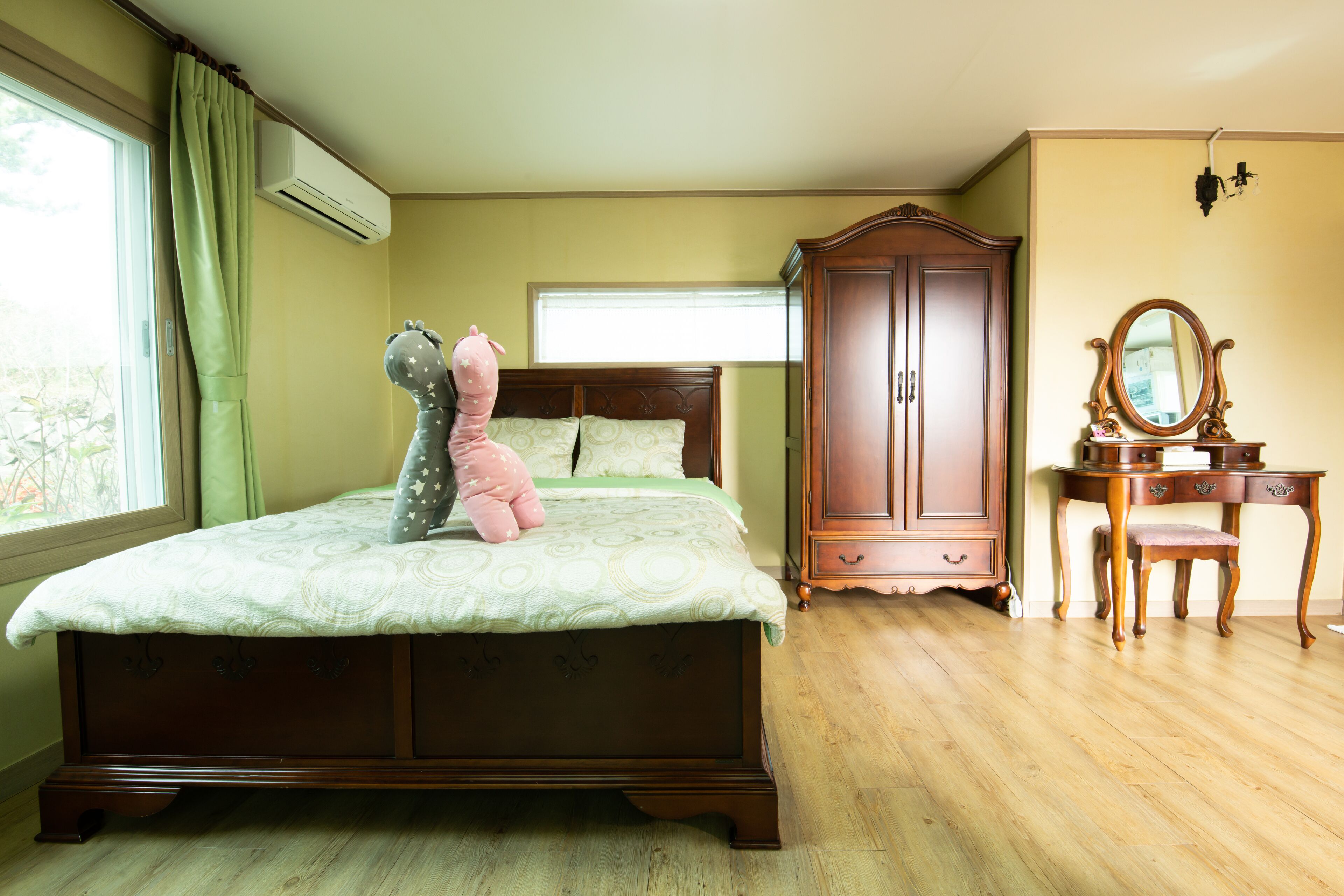 A bedroom with a bed, a dresser, a mirror, and a window with curtains.