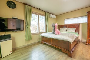 A bedroom with a wooden bed, a television, and a small air conditioner. - Lionhill Pension (Seogwipo)