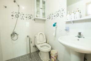 A bathroom with a toilet, shower, sink, and a cabinet with toiletries. - Lionhill Pension (Seogwipo)