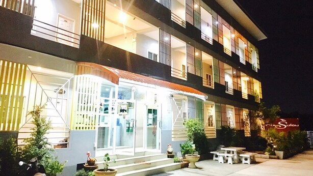 A multi-story hotel with balconies, a covered entrance, and outdoor seating. - The Rich Home (Nakhon Ratchasima)