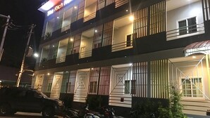 A multi-story hotel with balconies, a sign reading "The Rich Home," and parked vehicles. - The Rich Home (Nakhon Ratchasima)