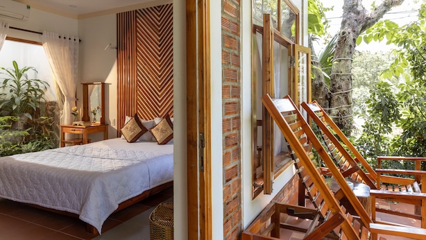 Un dormitorio con cama, cabecera de madera y vistas a espacios verdes.