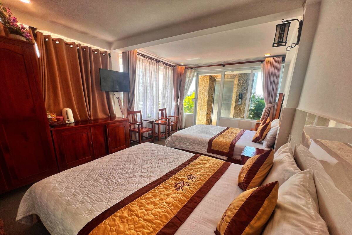 Hotellihuone, jossa on kaksi sänkyä, työpöytä, tuoli ja televisio.