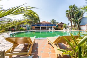 A pool area with lounge chairs and a building in the background.