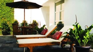 Un patio con dos sillones de madera, una mesa y una sombrilla.