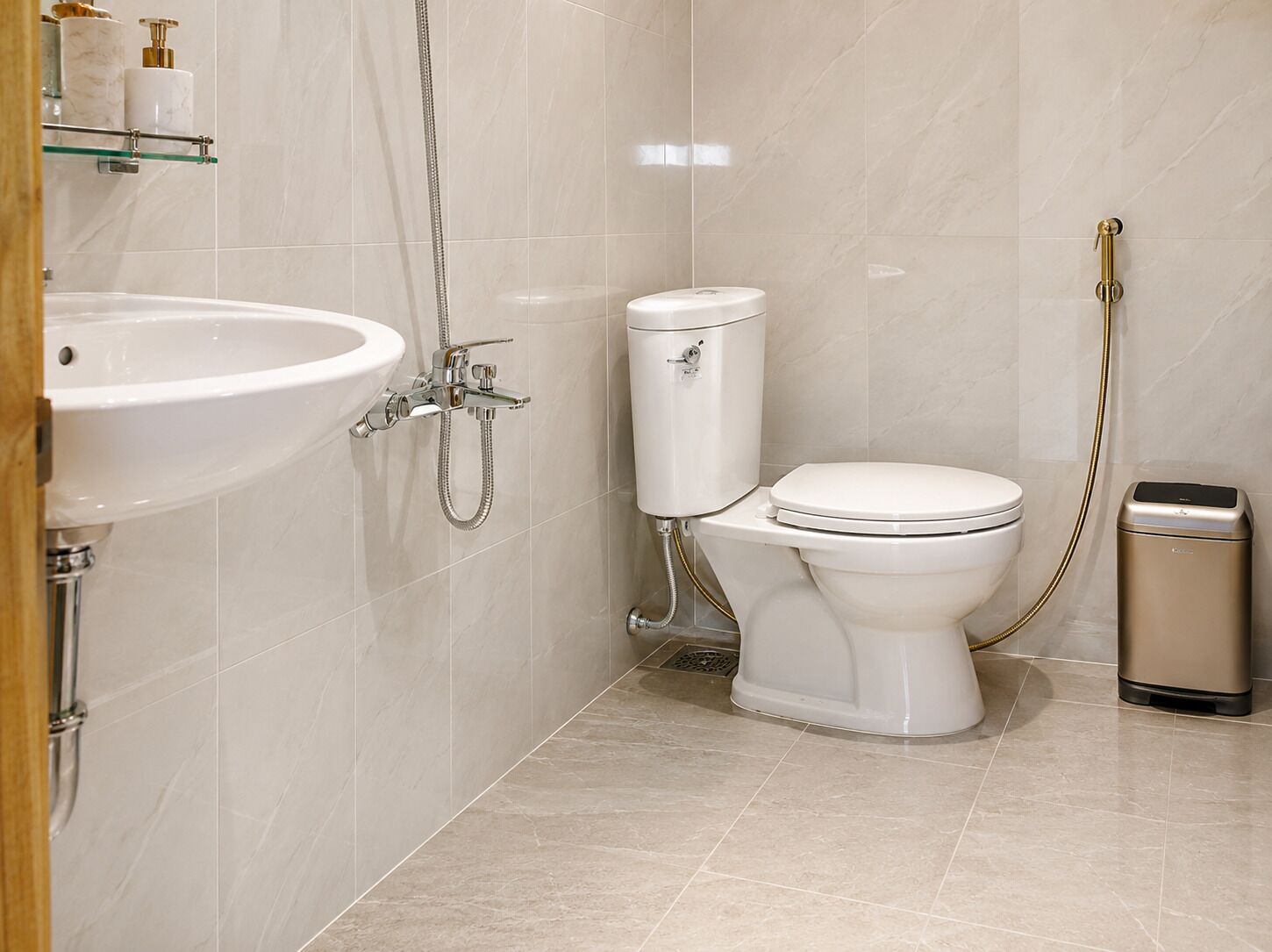 A bathroom with a white sink, toilet, and bidet, all with chrome fixtures.