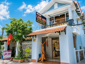 A two-story building with a sign for 'LAM ANH HOAMESTAY' and a flag. - The Lam Homestay (Phu Quoc)