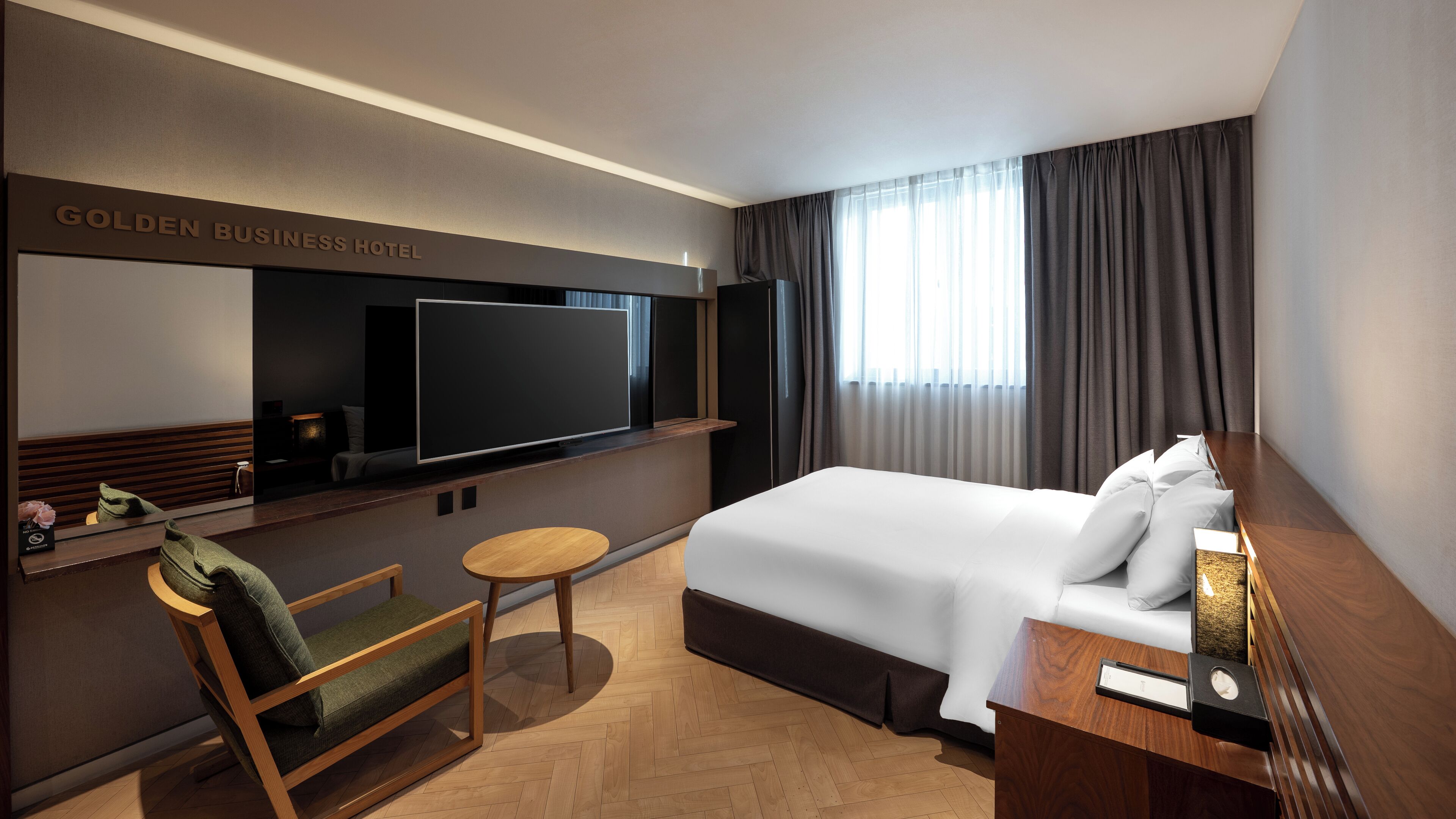 Une chambre d’hôtel avec un grand lit, un téléviseur fixé au mur, une petite table et une chaise.