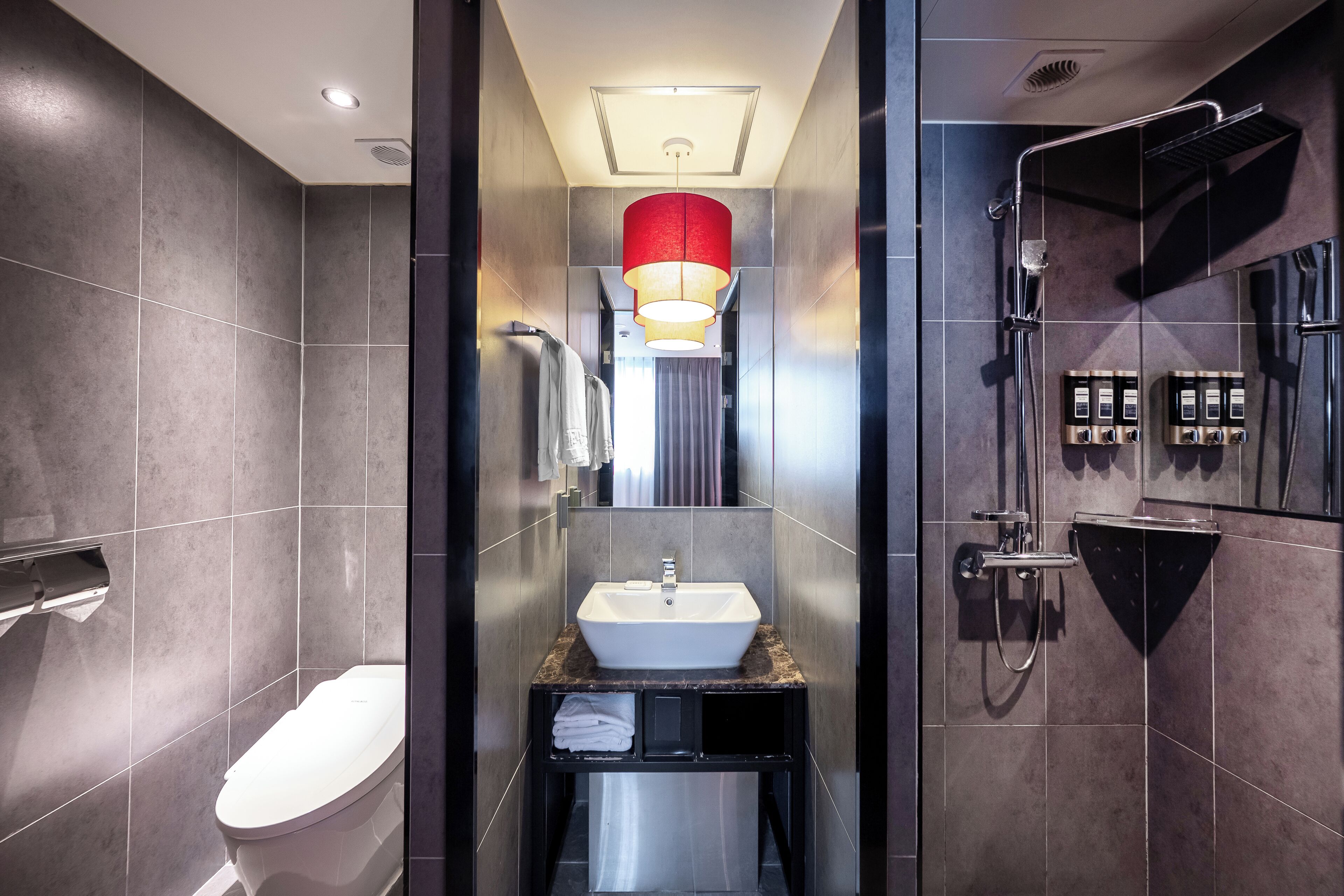 A modern bathroom with a white sink, a toilet, and a shower area.