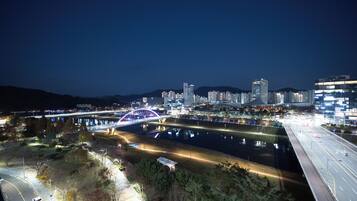 Un paisaje urbano nocturno con un puente iluminado destacado, un río y edificios altos.