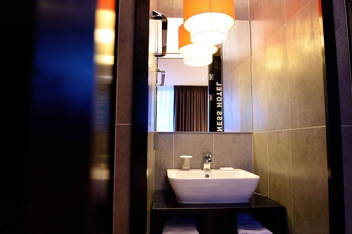 A modern bathroom with a white sink, a mirror, and a towel rack.