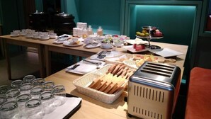 A breakfast buffet with various food items, a toaster, and glassware on a wooden table. - The Link 83 Mandalay Boutique Hotel (Mandalay)