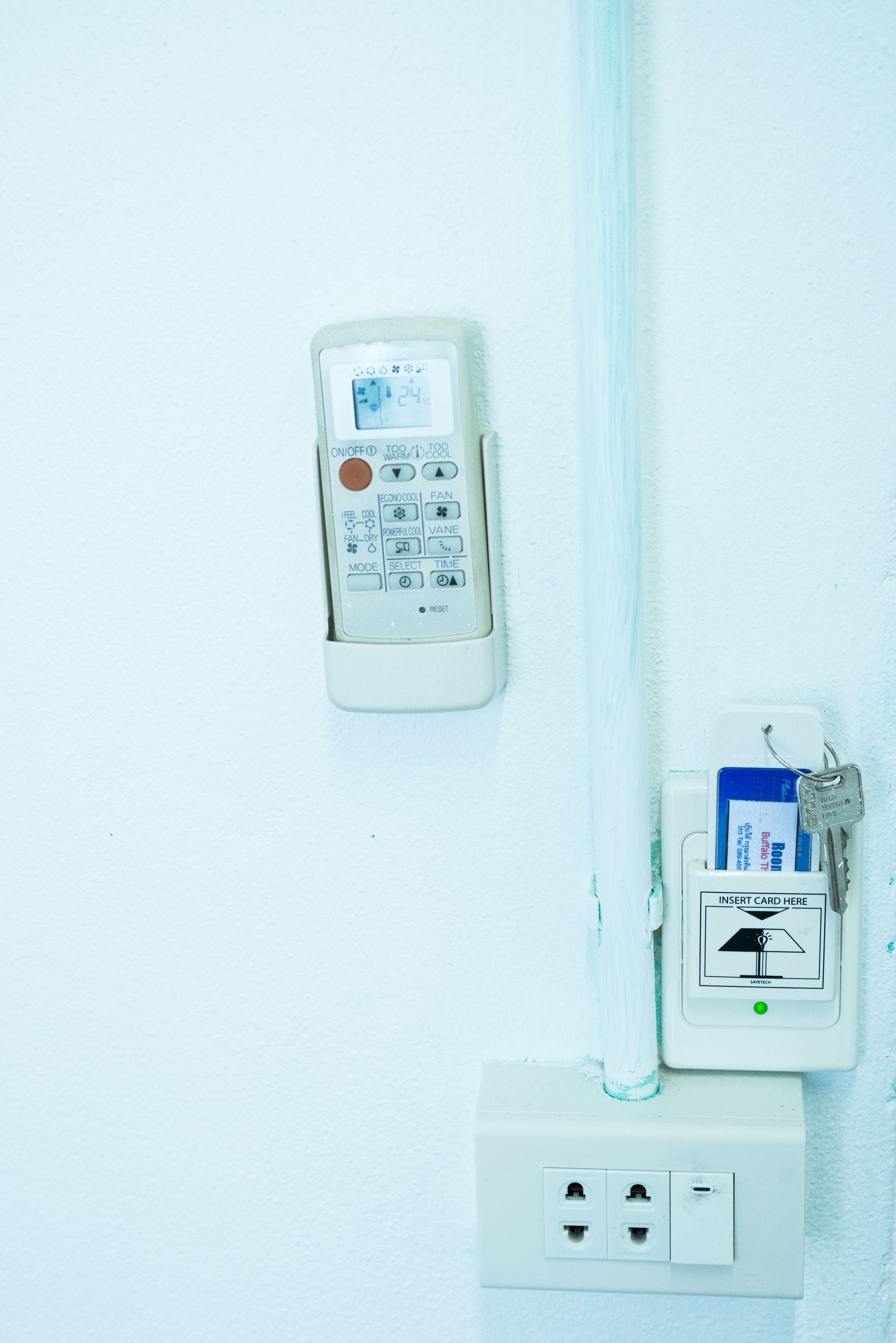 A wall-mounted thermostat and a card reader with a keycard inserted, connected to a power outlet.