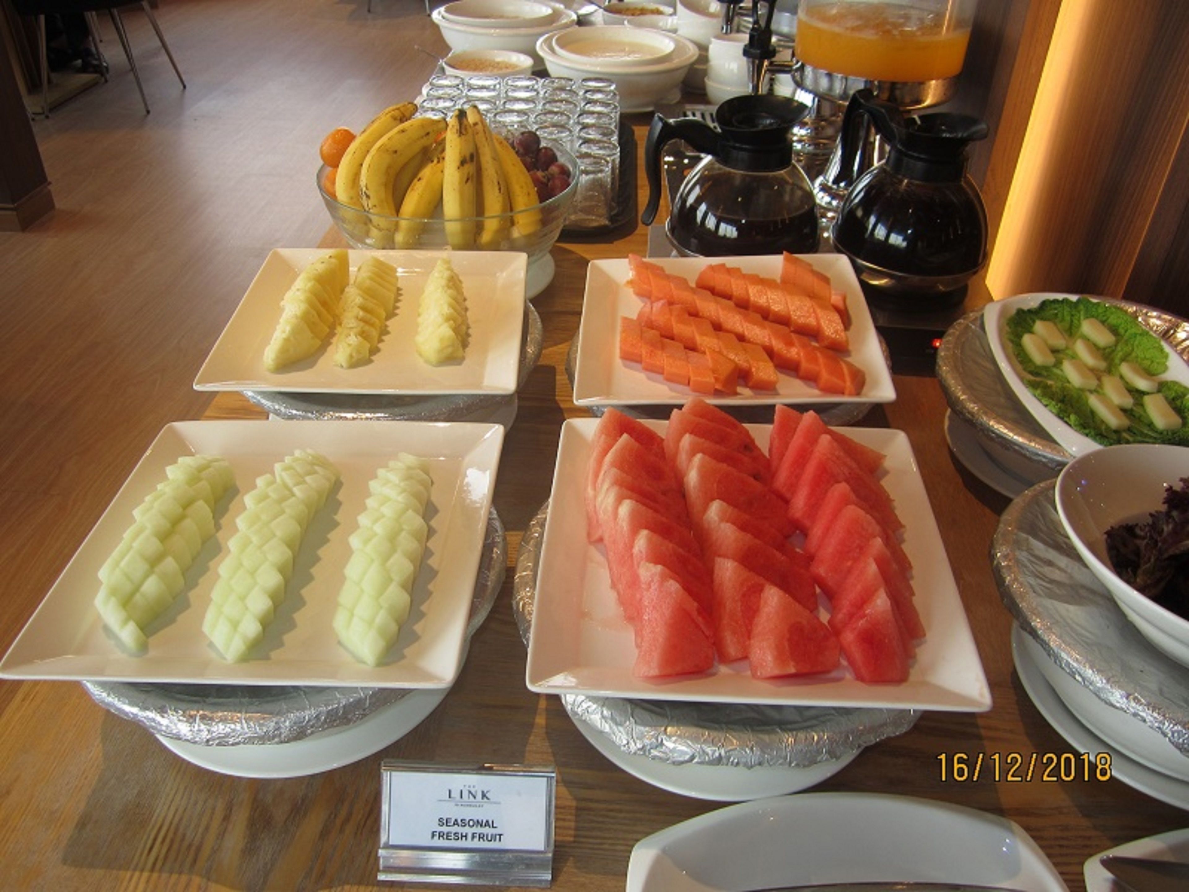 A buffet table with various fruits and beverages.