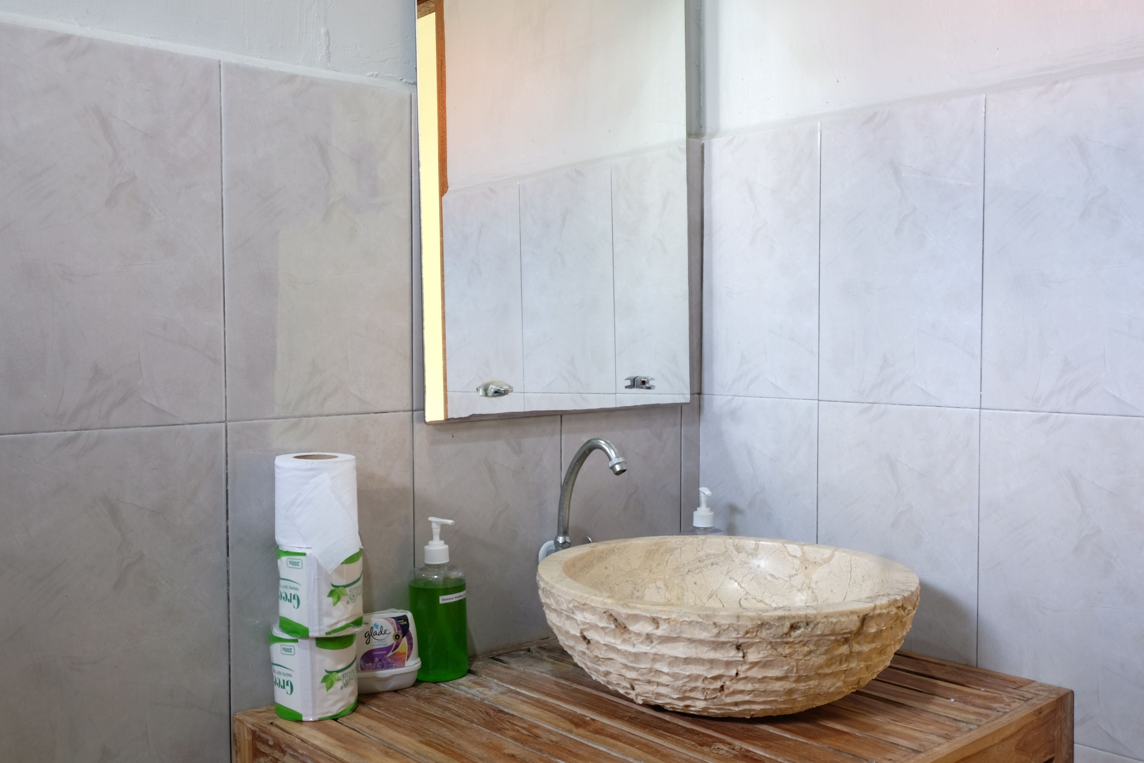 Une salle de bain avec un lavabo en marbre, un meuble-lavabo en bois, un miroir et des articles de toilette.