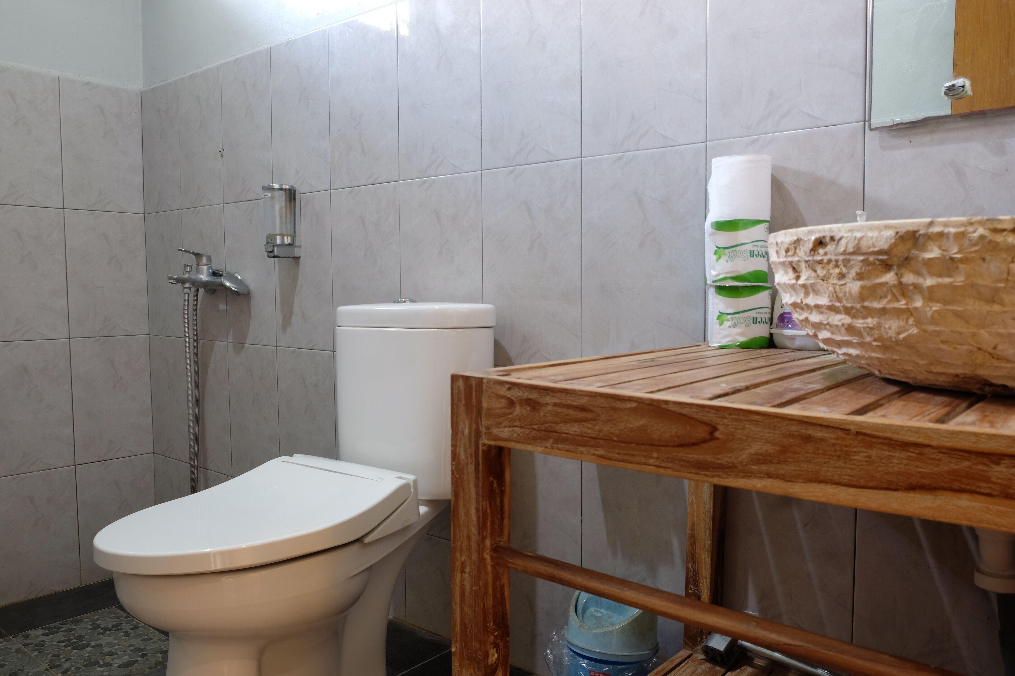 Ein Badezimmer mit Toilette, Dusche und einem Holztisch mit Waschbecken.