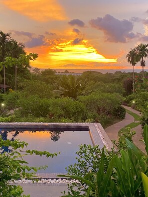 A pool surrounded by lush greenery and a sunset view. - Atmaland Resort (Kep)