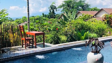 Relax by the serene pool surrounded by lush tropical vegetation and a decorative planter.