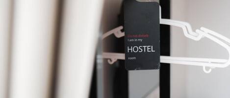 A black tag on a hanger with the text "Do not disturb. I am in my HOSTEL room."