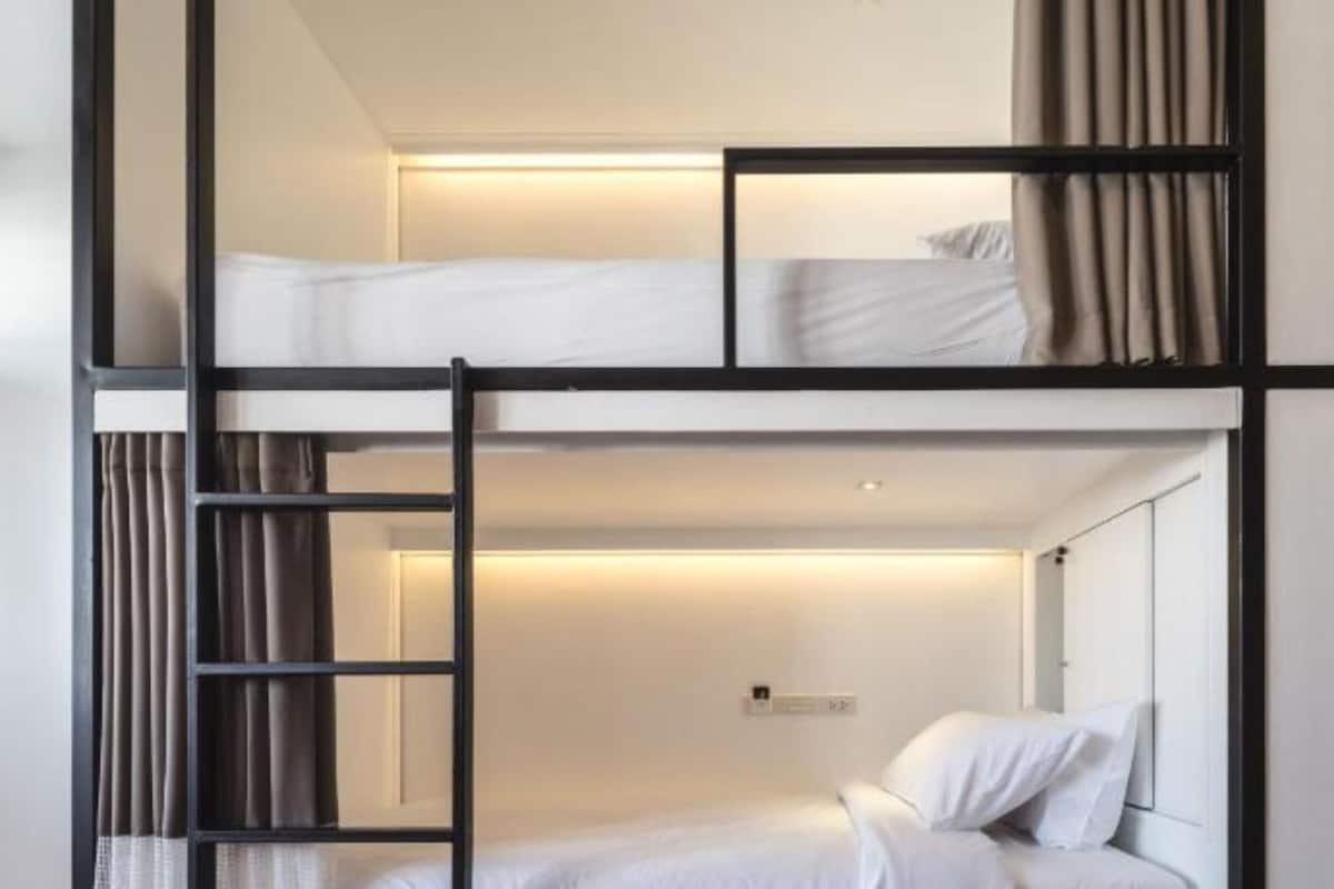 A bunk bed room with a ladder, a bedside table, and a nightstand.