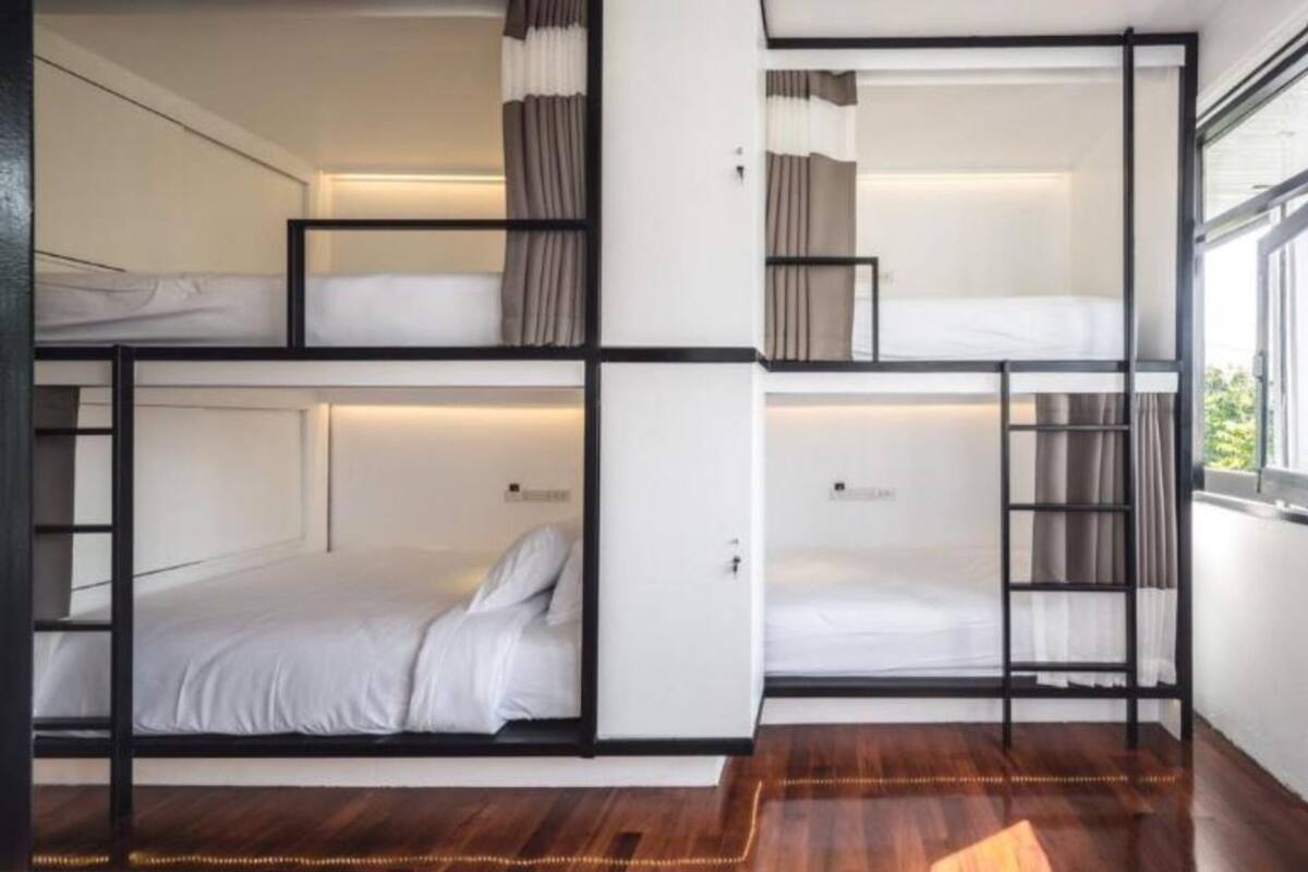 A modern, multi-level bunk bed room with built-in storage and a large window providing natural light.