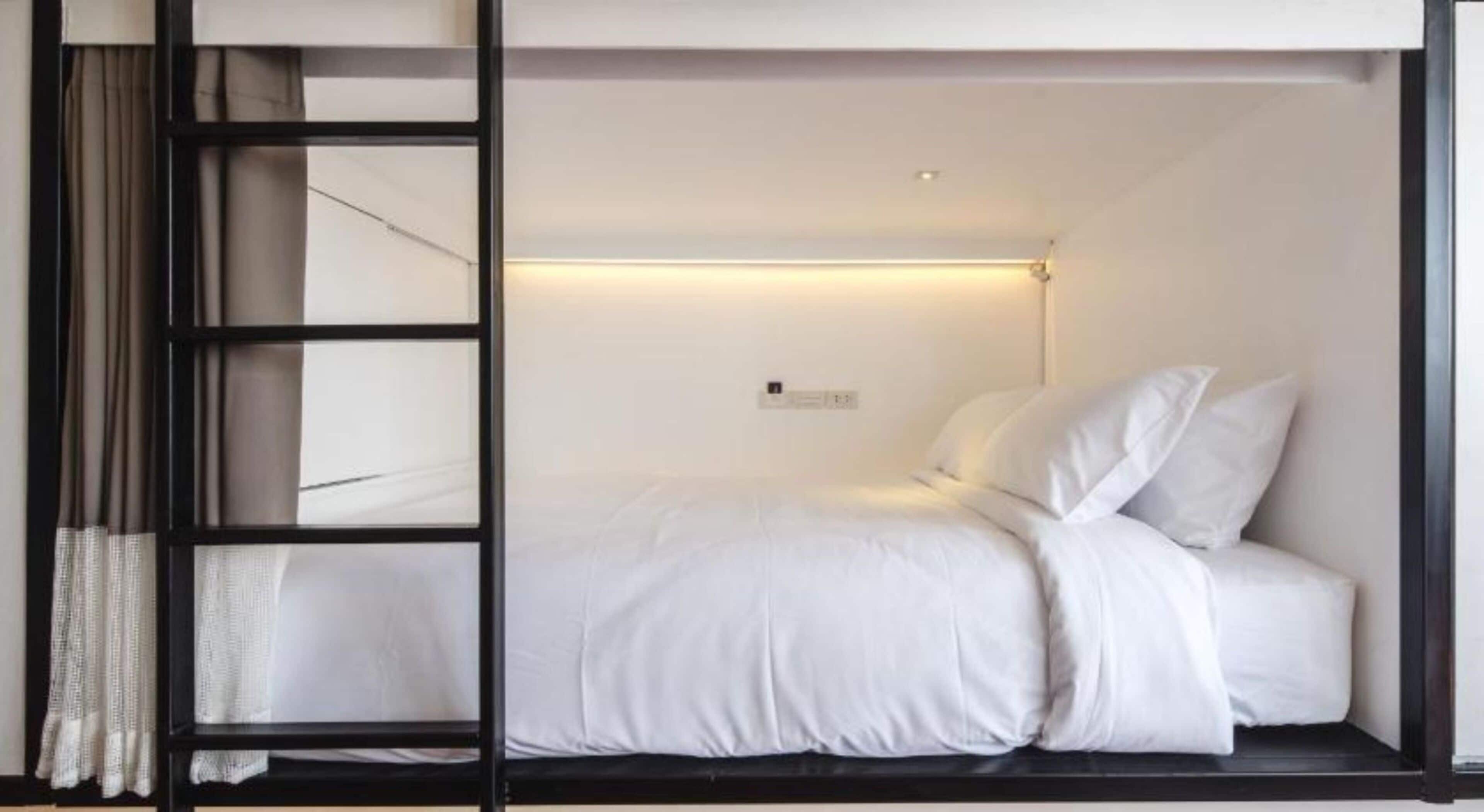A single bed with white bedding in a room with a black frame and a small bedside table.