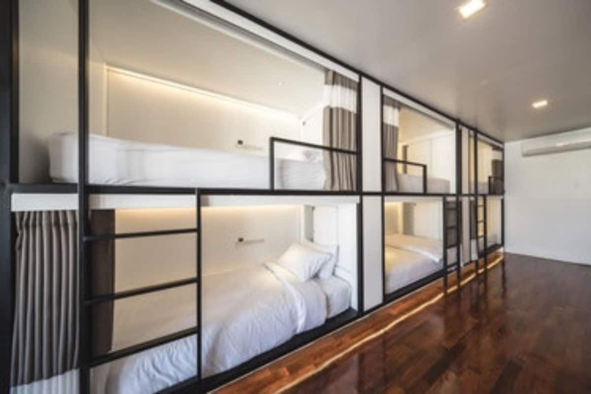 A modern hotel room with a bunk bed, a wooden floor, and a white wall.