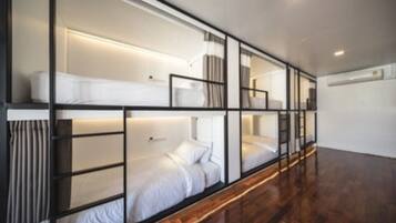 Una habitación de hotel moderna con una cama litera, suelo de madera y pared blanca.
