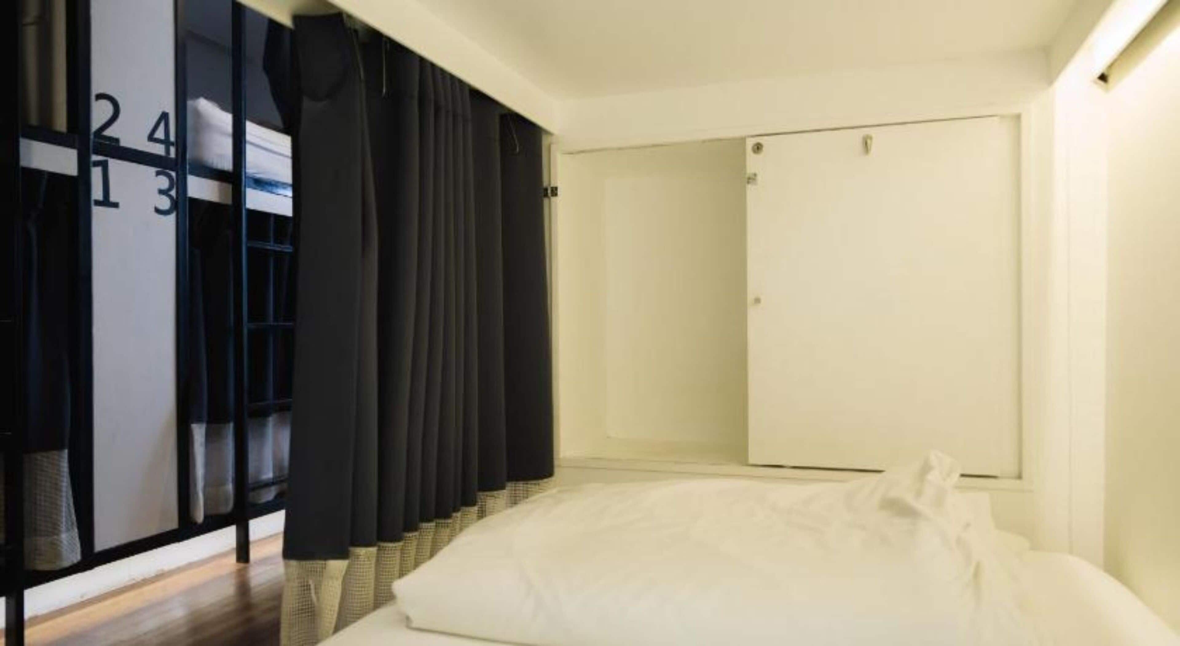 Una habitación de hotel con cama, armario y un espejo grande.