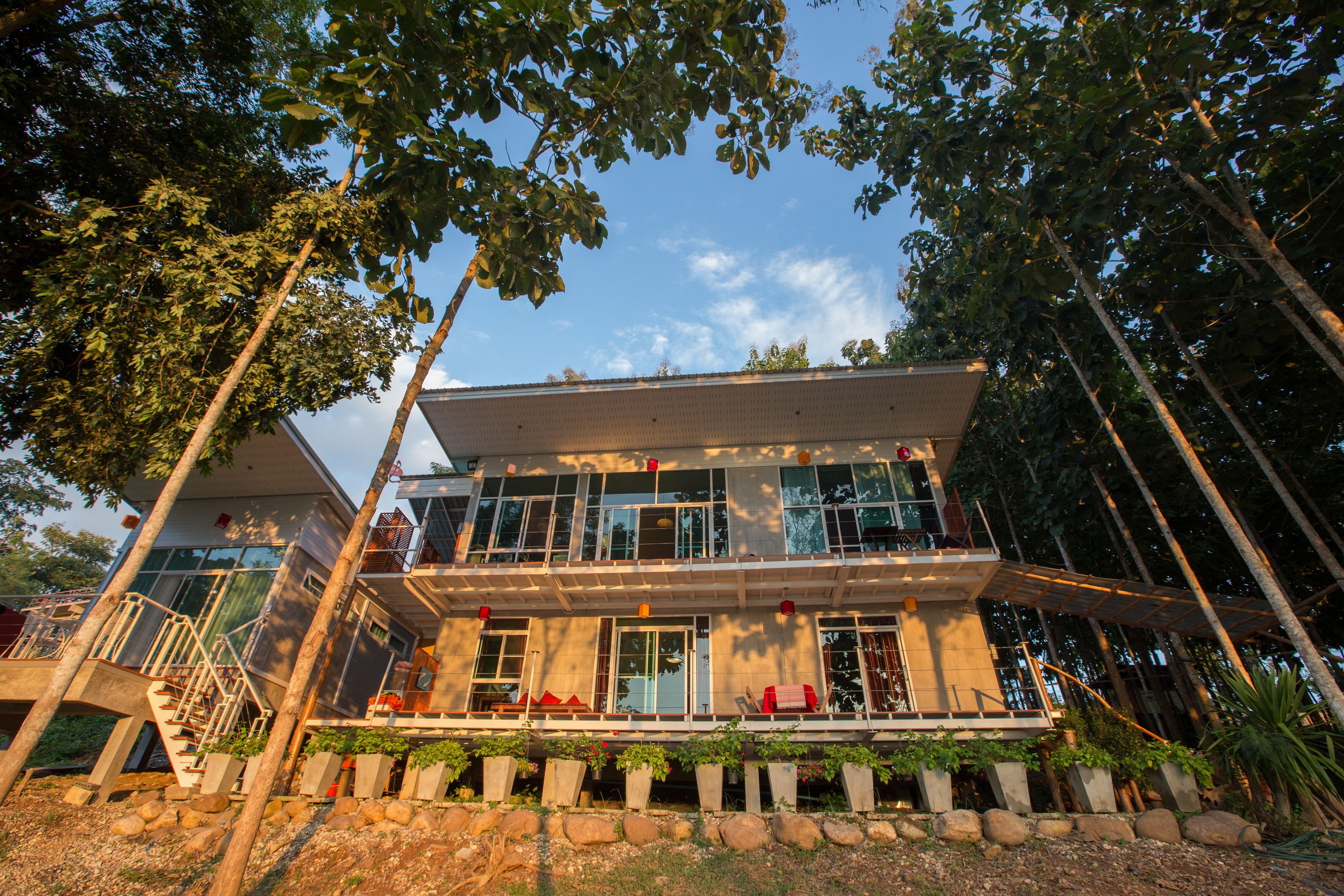 A modern two-story building with a balcony, large windows, and a stone foundation.