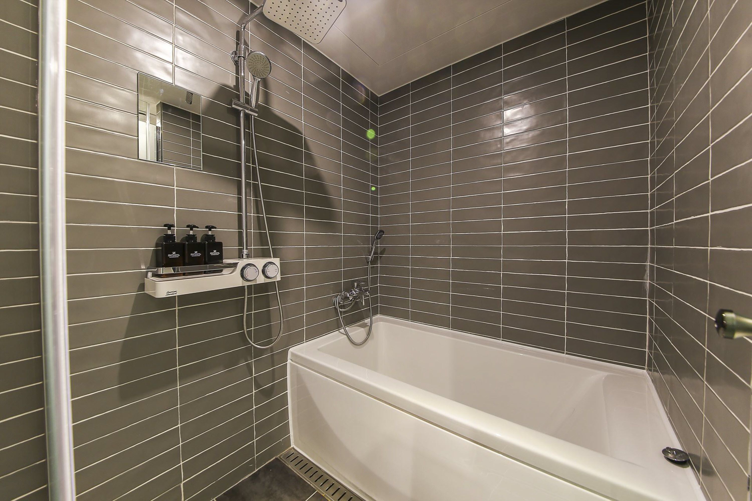 Un baño con bañera, ducha y espejo.