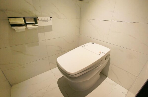 A modern bathroom with a toilet, a hand dryer, and a paper towel dispenser. - ZENITH HOTEL (Incheon)
