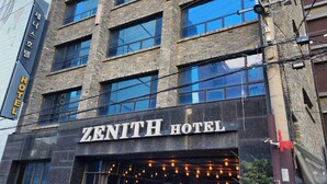 Een meerhoog gebouw met het bord "ZENITH HOTEL" duidelijk zichtbaar.