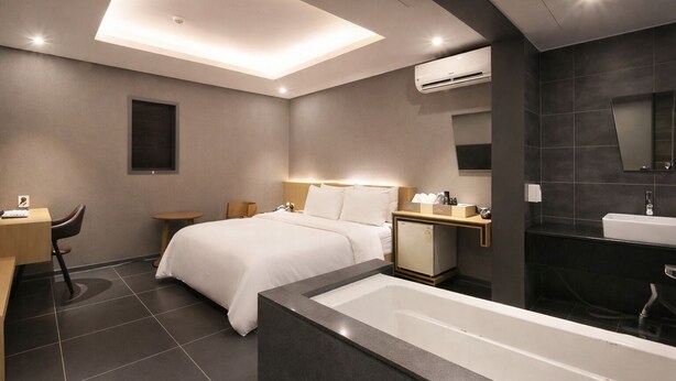 Een moderne hotelkamer met een bed, bureau, stoel en een groot bad.
