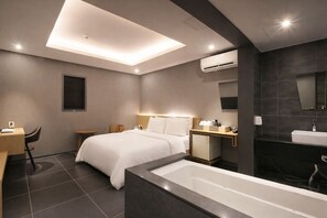 A modern hotel room with a bed, desk, chair, and a large bathtub. - ZENITH HOTEL (Incheon)