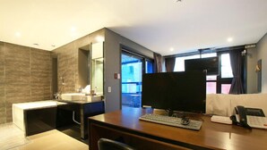 Een moderne hotelkamer met een bureau, computer, telefoon en een groot raam met uitzicht.