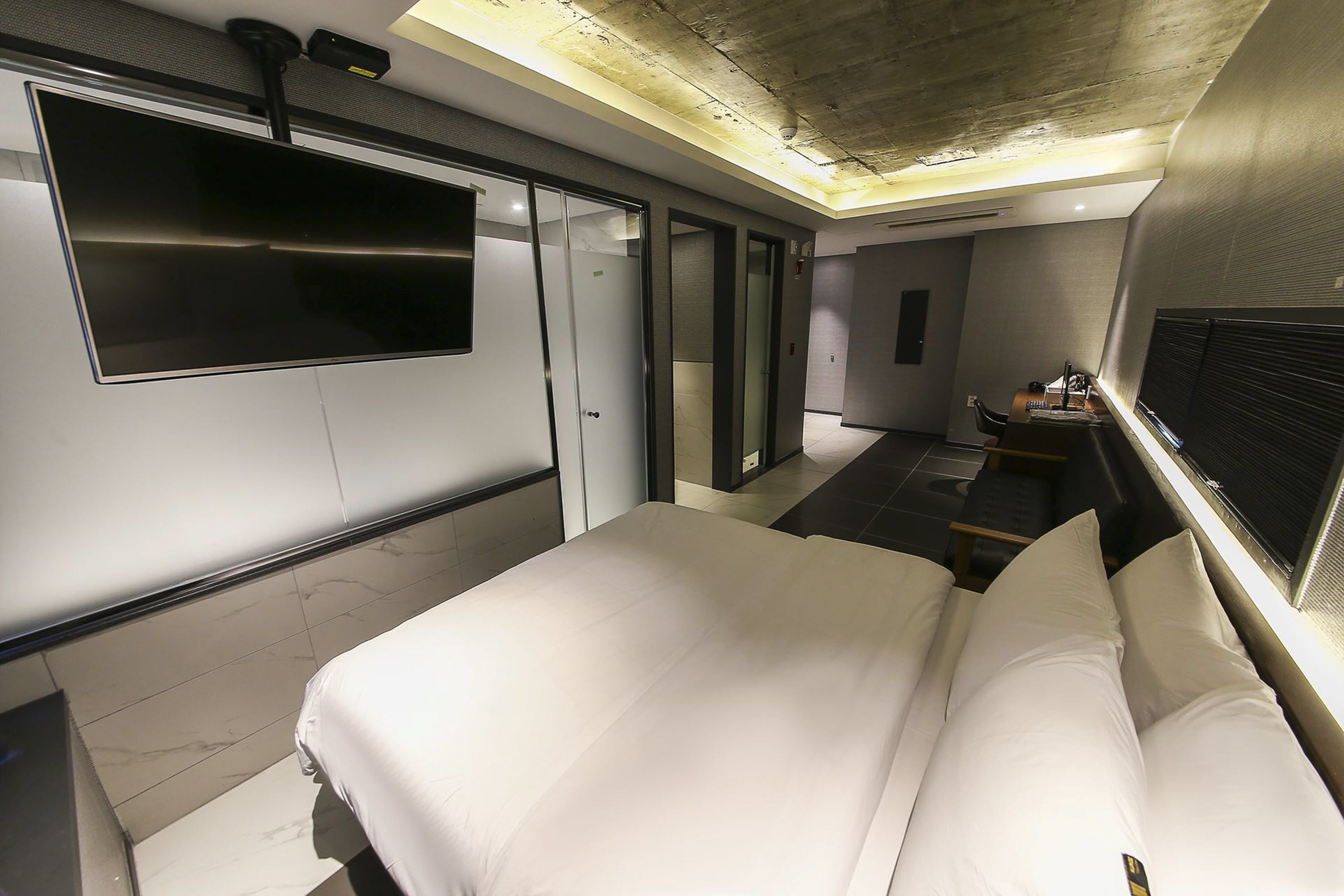 A modern hotel room with a large bed, a flat-screen TV, and a desk with a chair.
