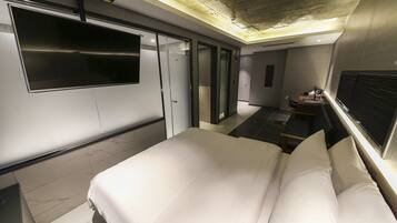 A modern hotel room with a large bed, a flat-screen TV, and a desk with a chair.