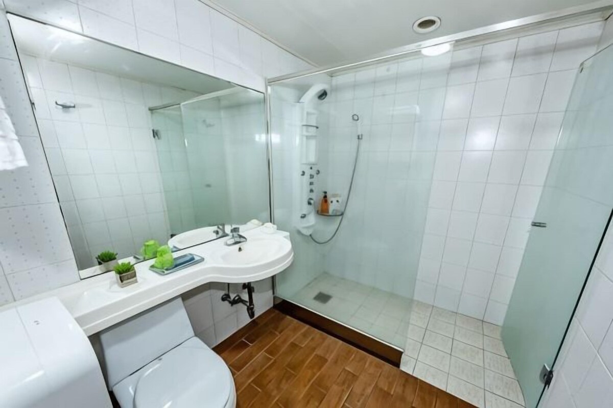 A modern bathroom with a glass-enclosed shower, a white sink, and a mirror.