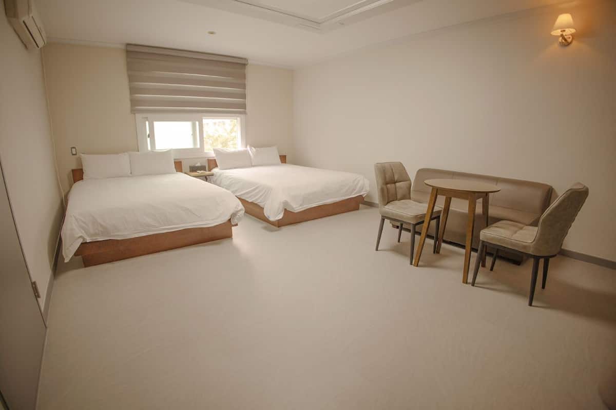 A hotel room with two beds, a small table with chairs, and a sofa.