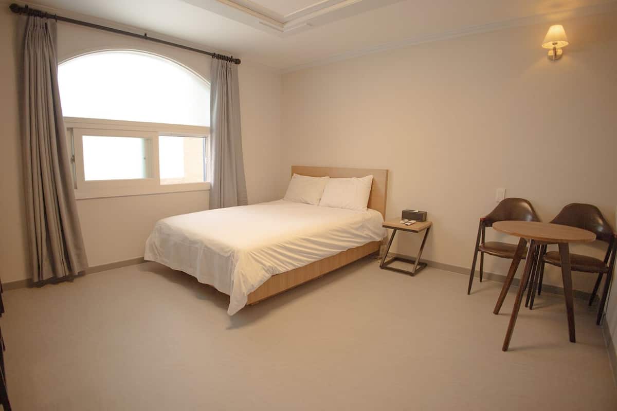 A neatly arranged bedroom with a bed, bedside table, and two chairs.