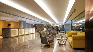 A lobby with a marble floor, a reception desk, a yellow sofa, and patterned chairs. - Cosmo Hotel Kuala Lumpur (Kuala Lumpur)