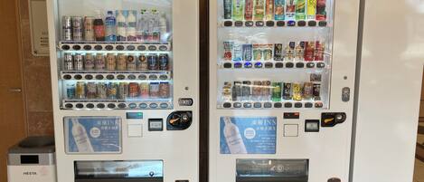 Two vending machines stocked with beverages and snacks.