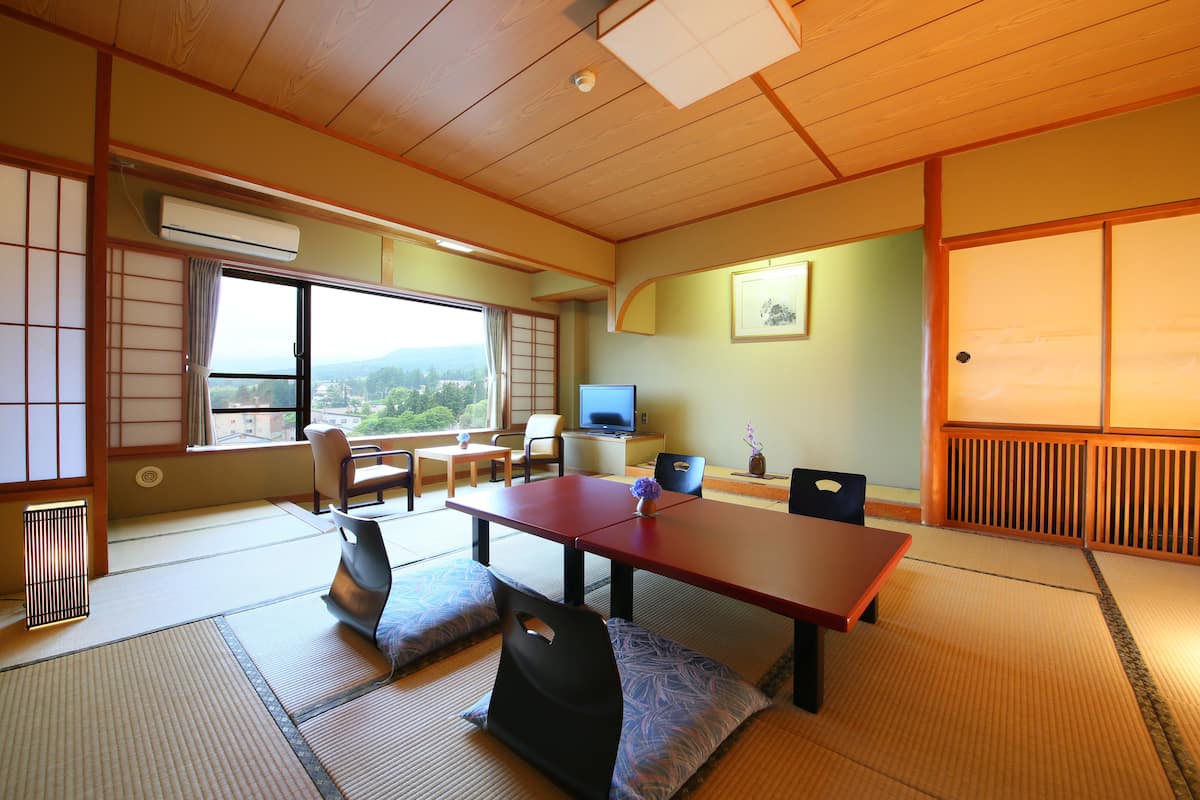 Une pièce de style japonais traditionnel, avec un sol recouvert de tatamis, une table basse et un téléviseur.